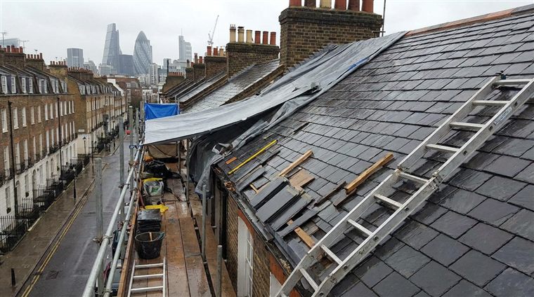 Roofers stripping and repairing a slate roof on a London terrace